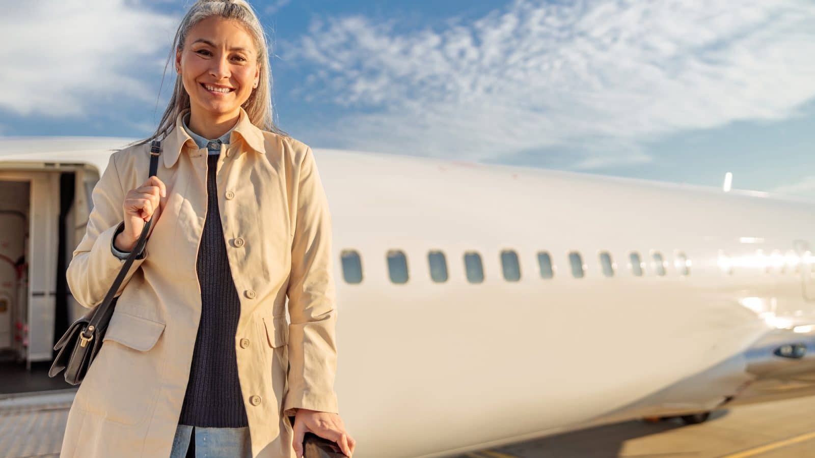 Joyful woman standing on aircraft stairs at airport