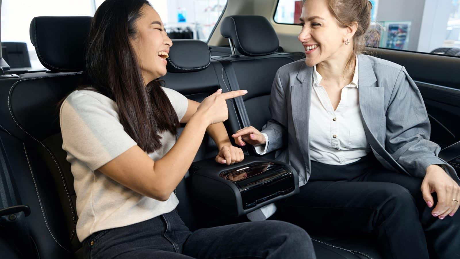 Two happy women at back seats in car